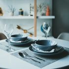 A modern dining table setup with plates, glasses, and cutlery in a stylish indoor setting.