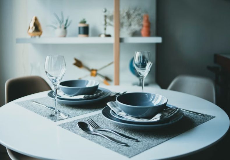A modern dining table setup with plates, glasses, and cutlery in a stylish indoor setting.