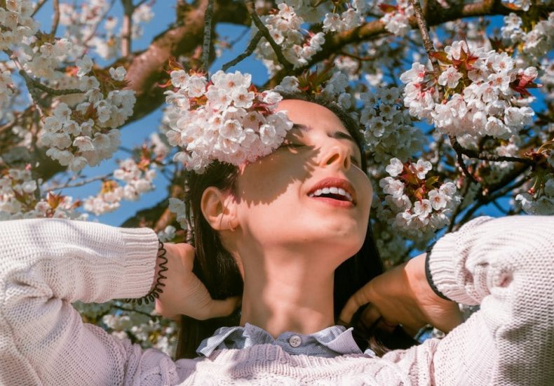 Woman relaxing under blooming cherry blossom tree